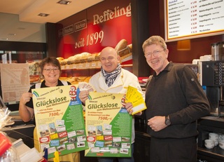 (von links nach rechts): Maria Schmalenbach, Geschäftsinhaber Joachim Reffeling und Gerhard Pöppel als Vertreter des Weezer Werberinges präsentieren gemeinsam die Plakate der Glückslosaktion in Weeze.